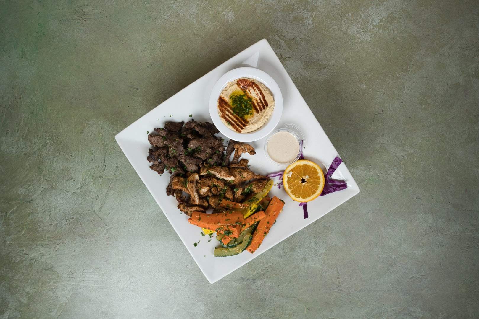 Beef shawarma carved and plated with hummus and pickled turnips at Phoenician Garden Fresno