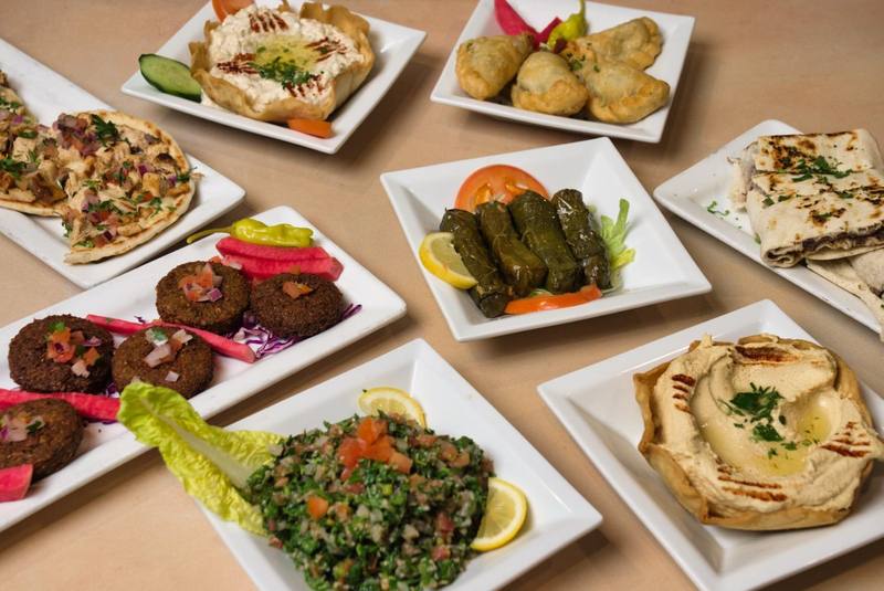 The Family Mezza spread: eight plates of dips, falafel, stuffed grape leaves, tabbouleh, cheese rolls, flatbread, and lavash