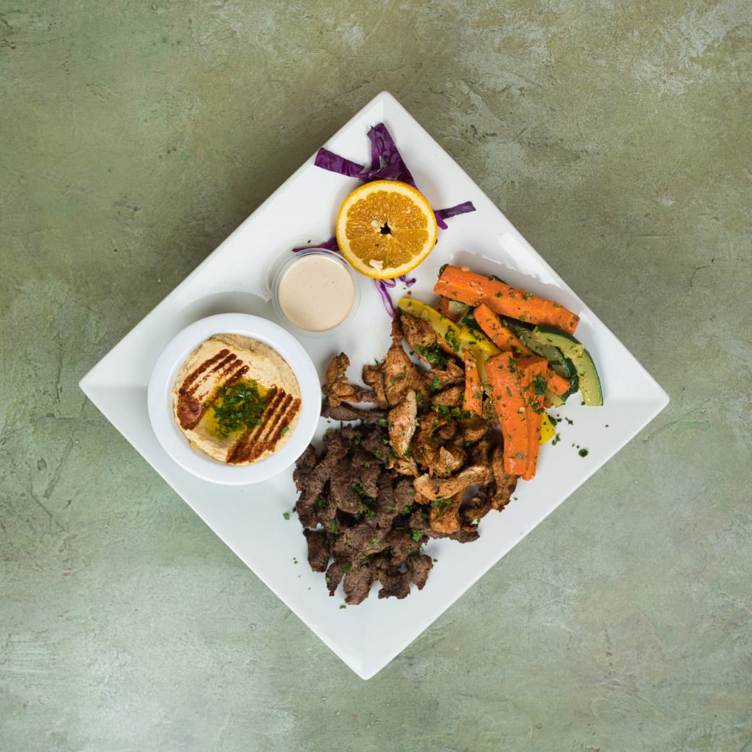 Half beef, half chicken shawarma plate with hummus, tahini, and grilled vegetables