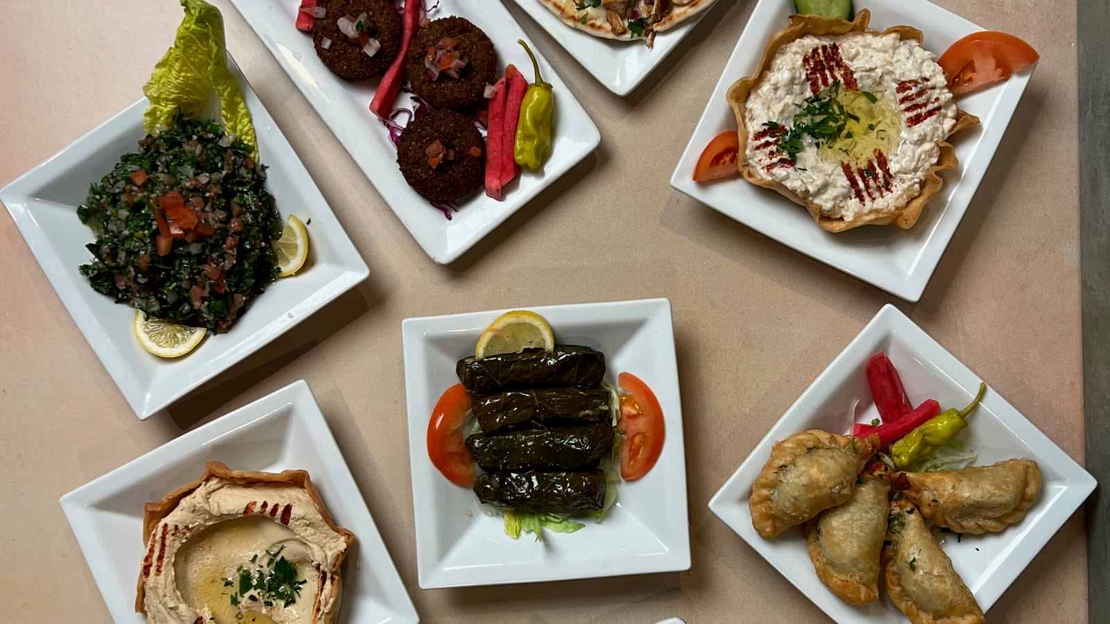 Family Mezza spread of hummus, baba ghannouj, falafel, tabbouleh, stuffed grape leaves, and warm pita at Phoenician Garden in Fresno